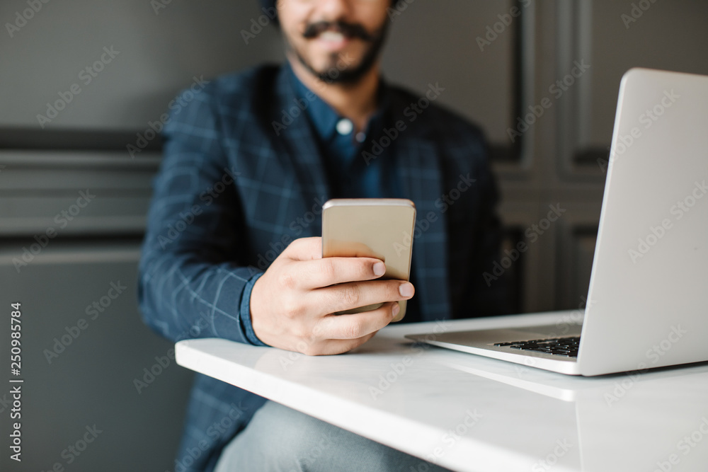 Unrecognisable businessman typing on his cell phone. Unrecognisable businessman typing on his cell phone.