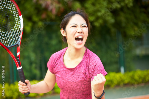 young asian female tennis player celebrating after scoring © imtmphoto