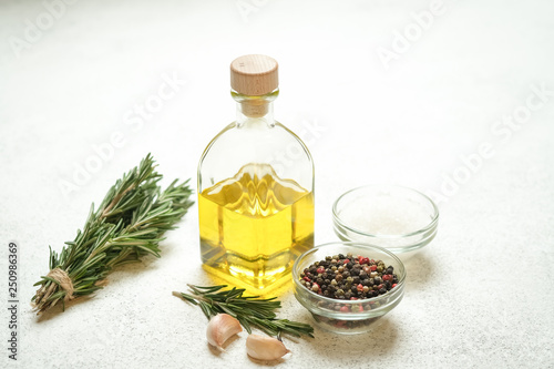 Fresh rosemary herb with oil and spices on a light background.
