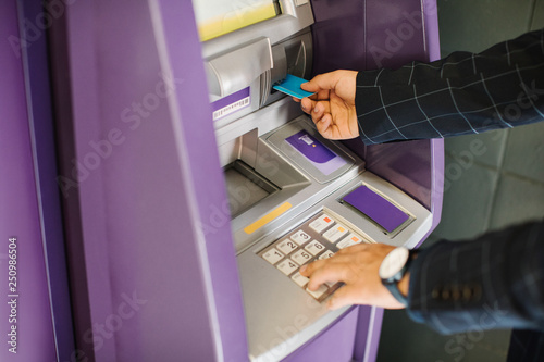Hands of unrecognisable businessman putting credit card in atm.