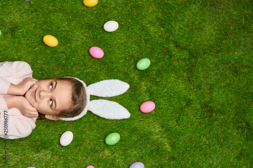 Girl lying on lawn near Easter eggs