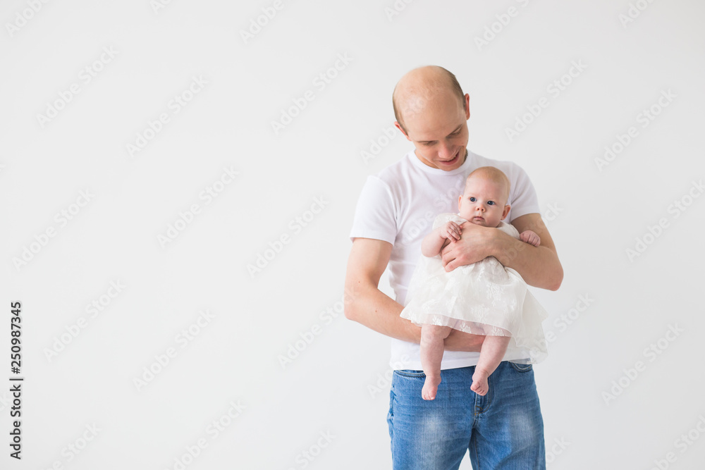 Parenting, family and fatherhood concept - Bald father hugging his little infant baby daughter on white background with copy space