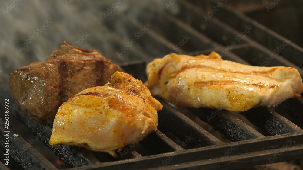 Meat grilled marinated in spices, turmeric, pepper, salt, two chicken fillets or turkey meat with grill prints and veal meat is medalled grilled, the tubers of smoke are torn from under the pieces of Meat grilled marinated in spices, turmeric, pepper, salt, two chicken fillets or turkey meat with grill prints and veal meat is medalled grilled, the tubers of smoke are torn from under the pieces of