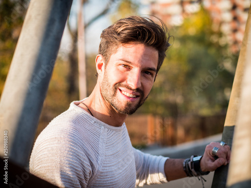 One handsome young man in urban setting in European city, standing and smiling to camera happy