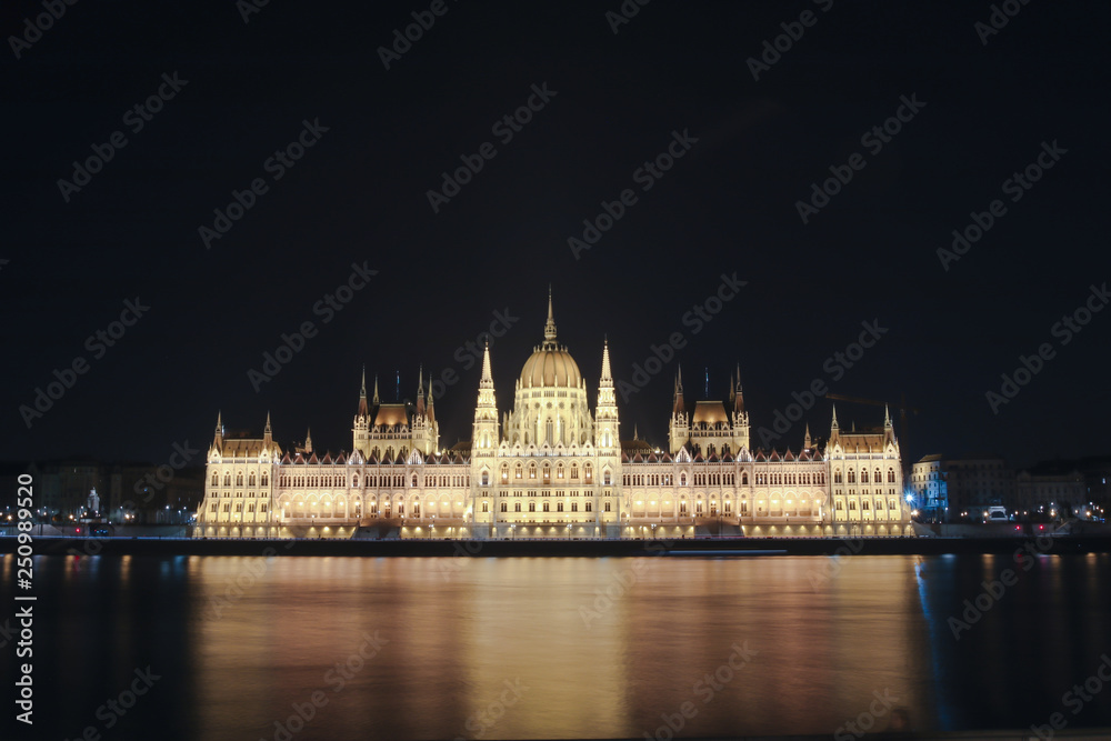 Illuminated Budapest parliament building at night with dark sky and reflection in Danube river 