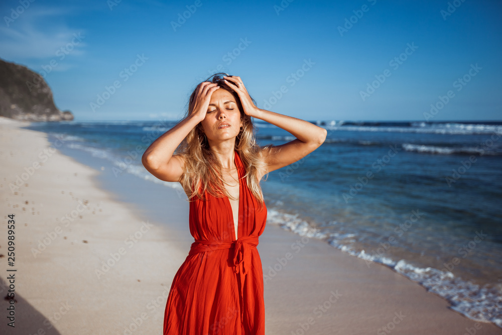 Girl holding her head on the beach suffering from the heat Girl holding her head on the beach suffering from the heat