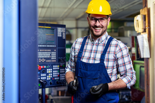 Portrait Of Male Engineer Operating CNC Machinery In Factory 