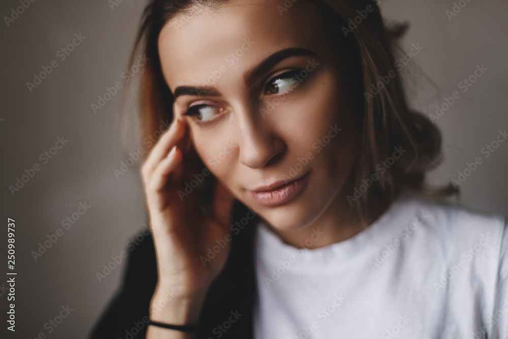 Beauty fashion portrait of young blond woman model with natural makeup and perfect skin posing in studio. Touching her face Beauty fashion portrait of young blond woman model with natural makeup and perfect skin posing in studio. Touching her face
