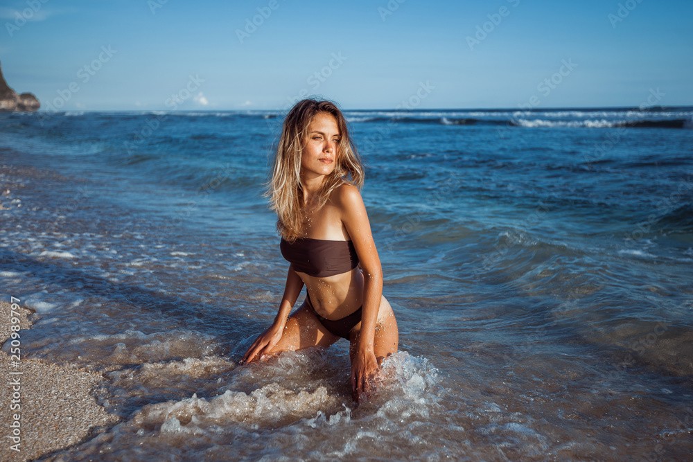 Girl sitting on her knees on the beach in the water Girl sitting on her knees on the beach in the water