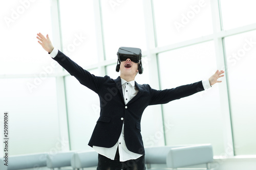 happy businessman in a helmet of a virtual reality standing in the office