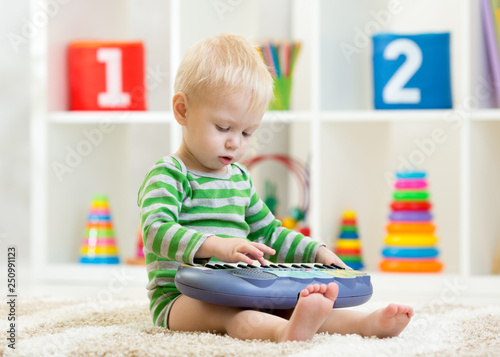 Kid boy plays toy piano sit...