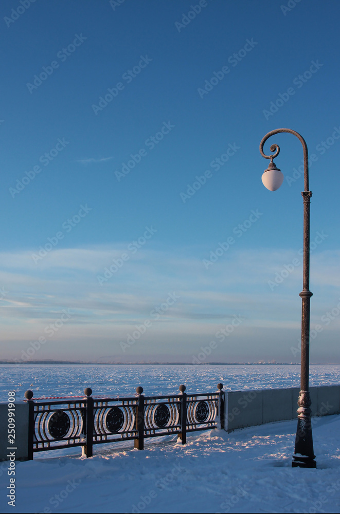 a lonely lantern on the snow-covered city embankment. Winter city landscape. Arkhangelsk, Northern Russia