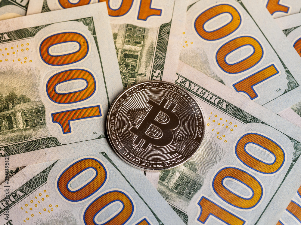 Background with crypto bitcoin and dollars. A symbolic coins of bitcoins on banknotes of one hundred dollars. Background with crypto bitcoin and dollars. A symbolic coins of bitcoins on banknotes of one hundred dollars.