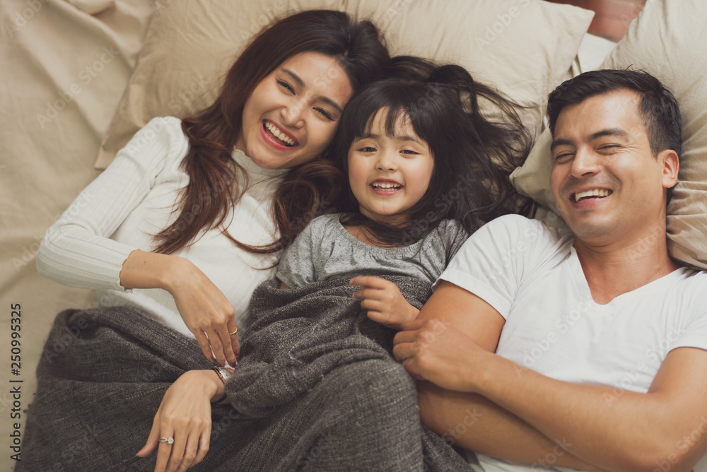 Young mother father and daughter enjoying with lying on the bed, happy family smiling at home. daughter with parents playing. see from top view. Young mother father and daughter enjoying with lying on the bed, happy family smiling at home. daughter with parents playing. see from top view.