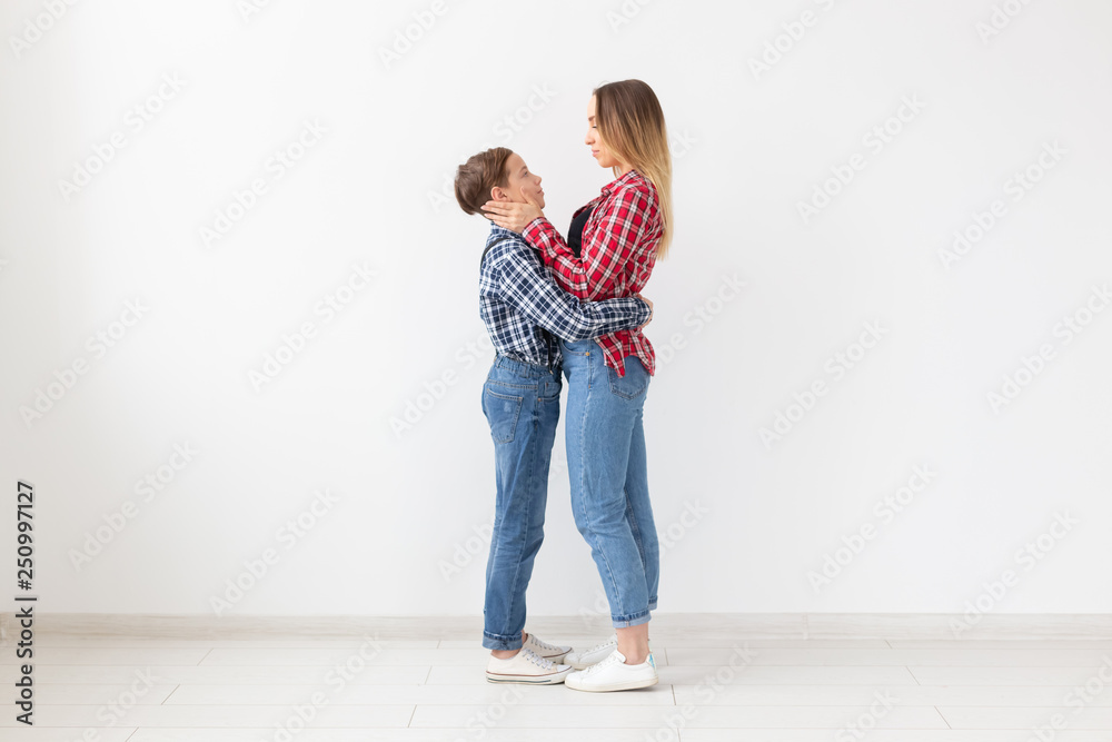 Family, fashion and mother day concept - teen boy hugging his mom on white background