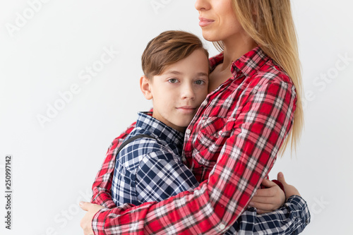 Mothers day, children and family concept - teen boy hugging his mom on white background