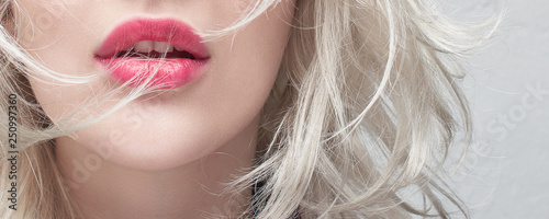 Close-up red plump lips of a young blonde woman on a white background. Cosmet...