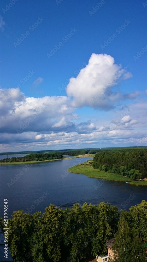 Blue sky and blue lake in summer. White clouds are reflected in the water. The famous lake Seliger. Russia.