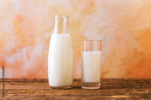 Glass and Bottle of fresh milk. Bottle with milk and glass of milk on wooden table.