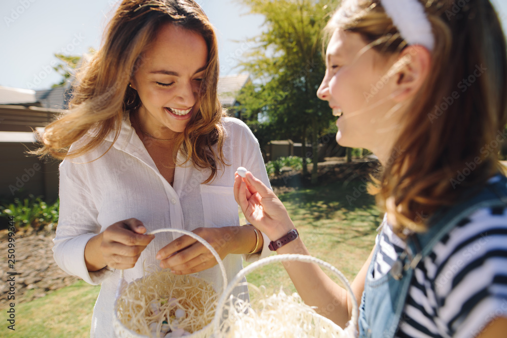 Fototapeta premium Mother and daughter walking in park carrying easter egg baskets