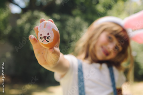 Canvas Print Girl showing a painted easter egg standing outdoors