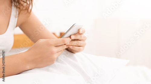 Millennial woman networking on cellphone in bed