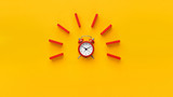 Alarm clock with red dominoes on yellow background