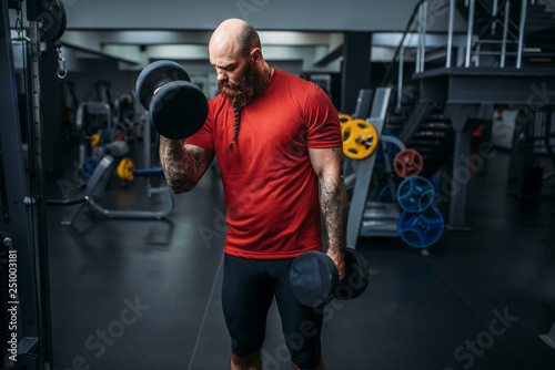 Athlete doing exercise with dumbbells in gym