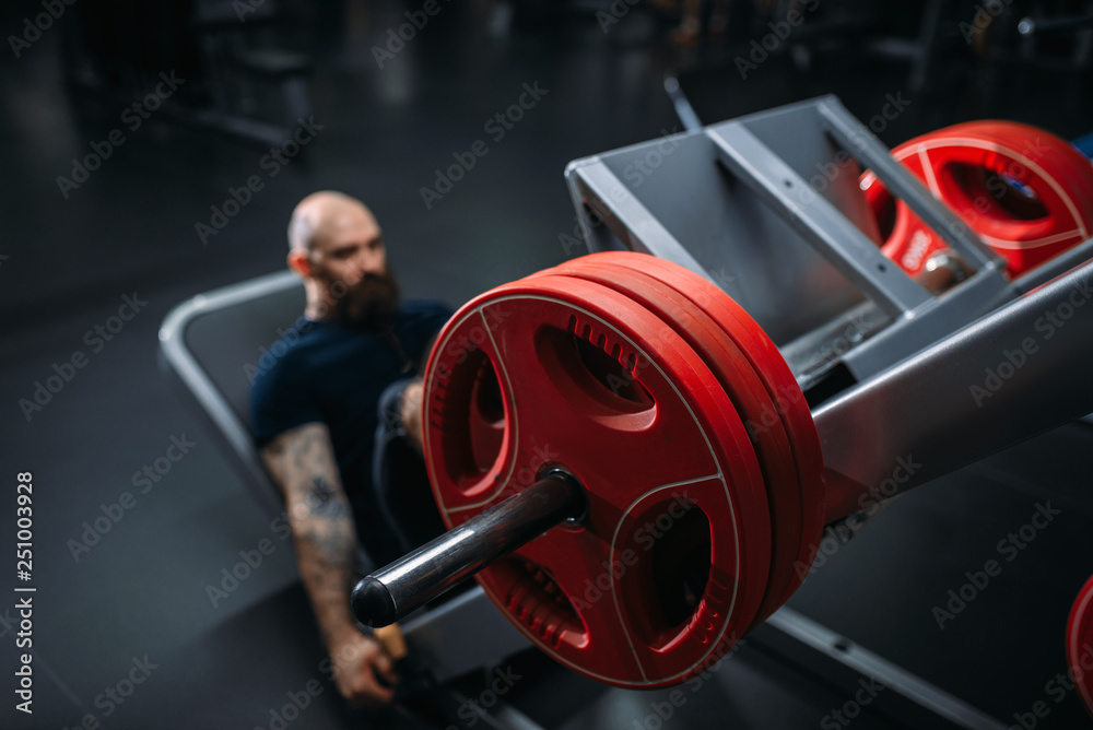 Muscular athlete on exercise machine with barbell