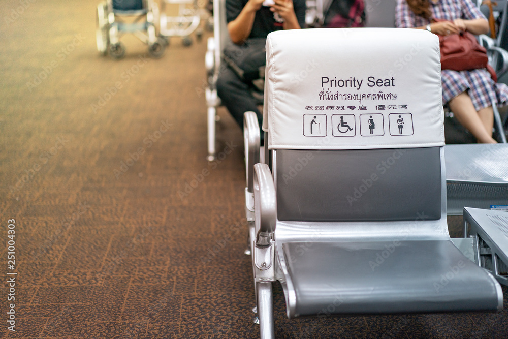 Obraz premium White and grey piority seat near gateway in the airport, with blur passengers behind. (Thai and Chinese language means 