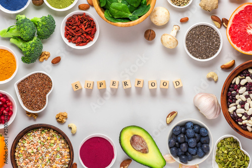 frame of superfood clean eating selection: fruit, vegetable, seeds, superfood, nuts, berries on white marble background