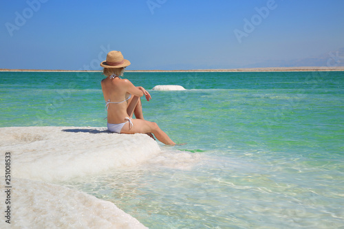 Attractive girl in bikini sitting on the shore of the dead sea