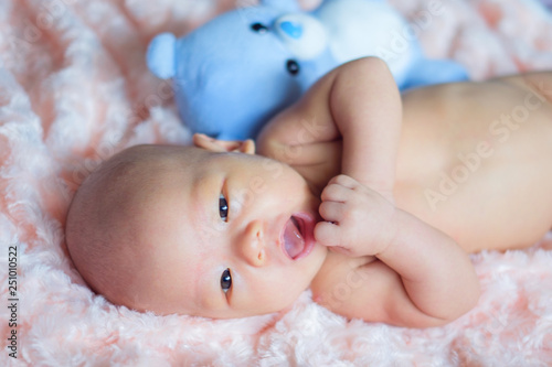 Happy Cute little Asian 2 months old newborn baby boy child is smiling with blue teddy bear toy and looking at camera, Newborn child relaxing in bed. Soft and Selective focus photo