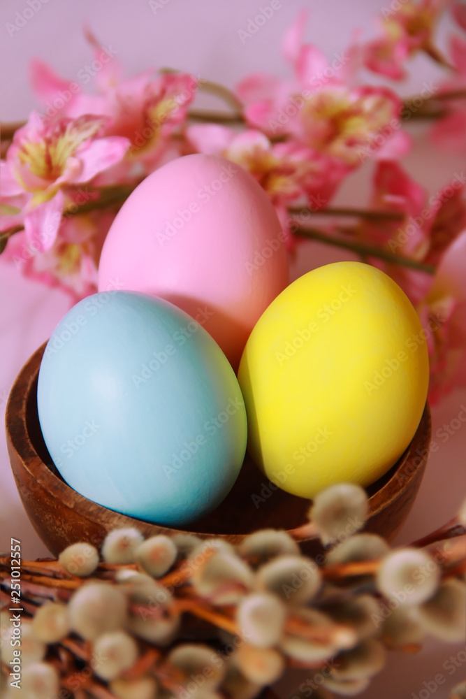 pink yellow blue eggs against a background of willow and flowers for the Easter holiday pink yellow blue eggs against a background of willow and flowers for the Easter holiday