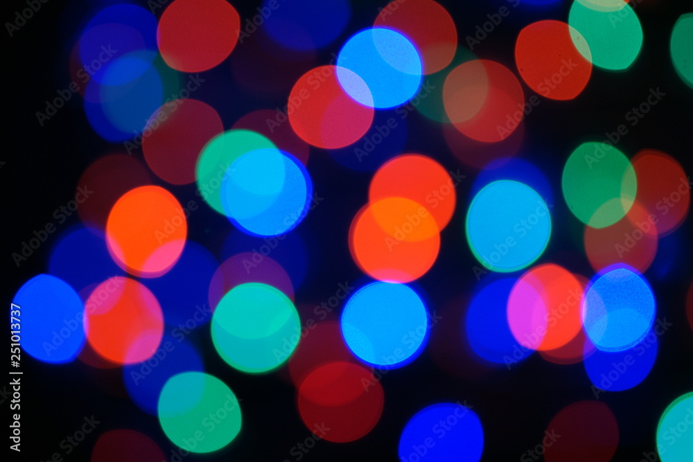 Multi-color blue holiday garland. Garland is blurred. Many big colorful round lights. Fully defocused photo. Blurred background and foreground. Holiday mood. New Year and Christmas is coming.