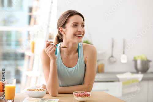Fotografie Young woman in fitness clothes having healthy breakfast at home
