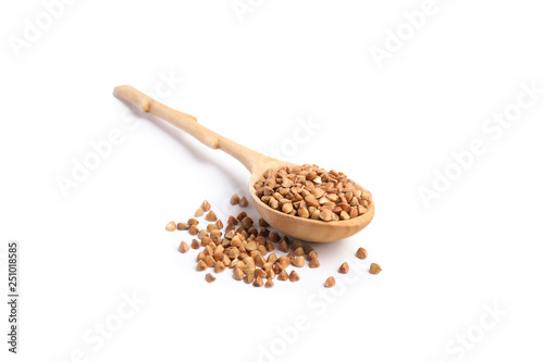 Spoon with uncooked buckwheat on white background