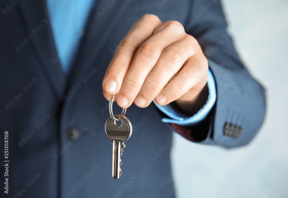 Young man holding key on color background, closeup Young man holding key on color background, closeup