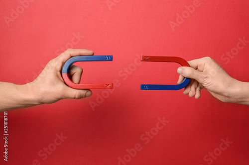 People holding magnets on color background, closeup