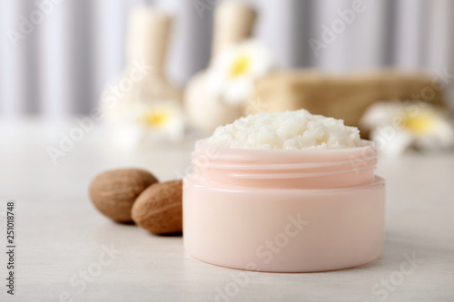 Jar of shea butter and nuts on table against blurred background. Space for text