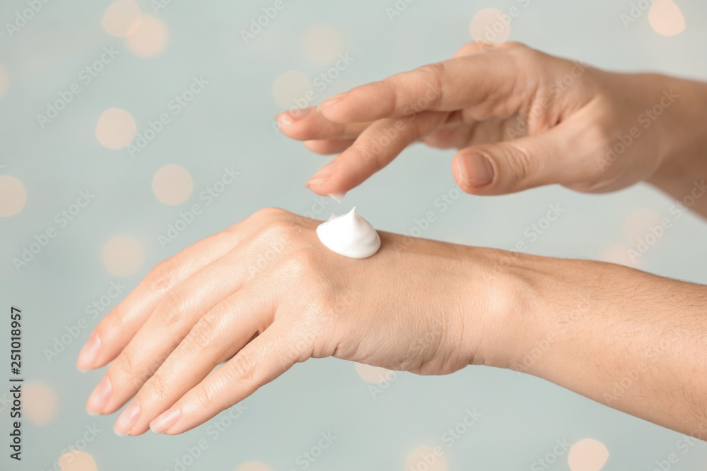 Woman applying hand cream on blurred background, closeup Woman applying hand cream on blurred background, closeup