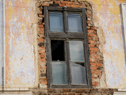 Wooden , broken window on abandoned crumbling brick house in Romania.