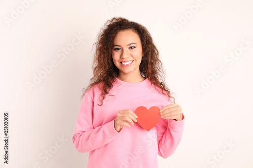 African-American woman with paper heart on white background