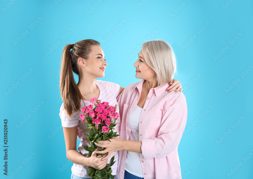 Young daughter congratulating her mature mother on color background. Happy Women's Day Young daughter congratulating her mature mother on color background. Happy Women's Day