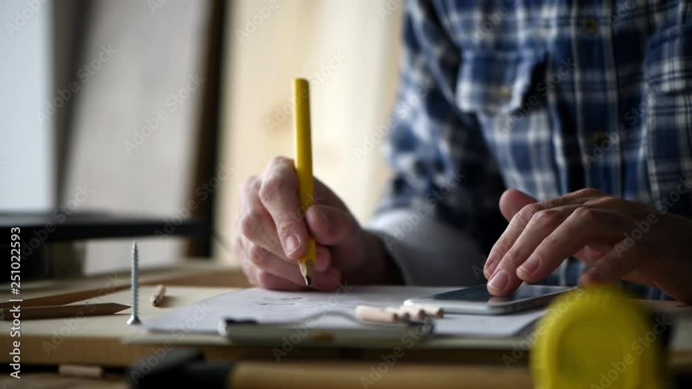 Carpenter making project calculation using smartphone app in small business woodwork workshop Carpenter making project calculation using smartphone app in small business woodwork workshop