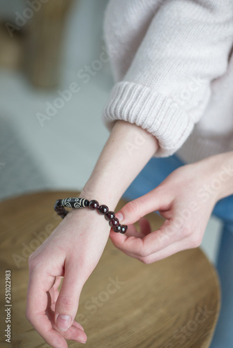 a bracelet of stones (garnet), bracelet of dark red, black stones on the hand, the girl touches the stones on the bracelet (vertically).