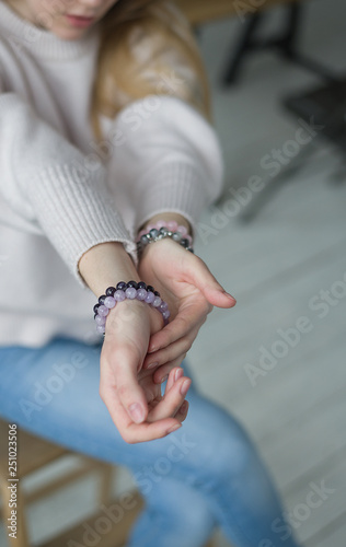 four bracelets of purple, pink, gray, stones on the hand, bracelets of amethyst, rose quartz, tourmaline quartz, sherl, charoite (vertically).
