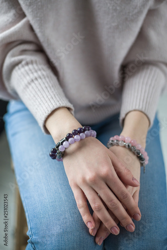 four bracelets of purple, pink, gray, stones on the hand, bracelets of amethyst, rose quartz, tourmaline quartz, sherl, charoite