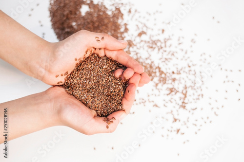 Seeds of flax is on the hands of a young girl on a light background. The concept of healthy food