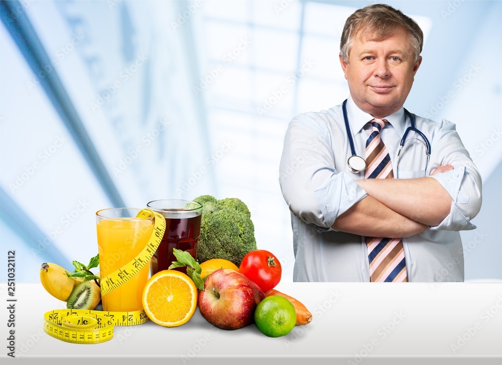 Fototapeta premium Young handsome dietology specialist with healthy food on table